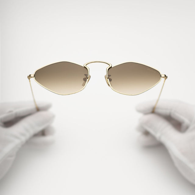 Another angle of gloves holding Austria Sunglasses Gold with Taupe Flat Gradient