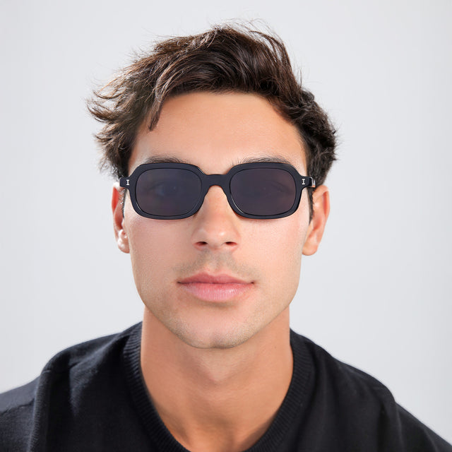 Man with brown hair in a black shirt wearing Berlin Sunglasses Black with Grey