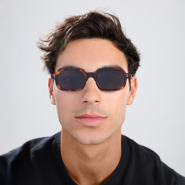Man with brown hair in a black shirt wearing Berlin Sunglasses Havana with Grey