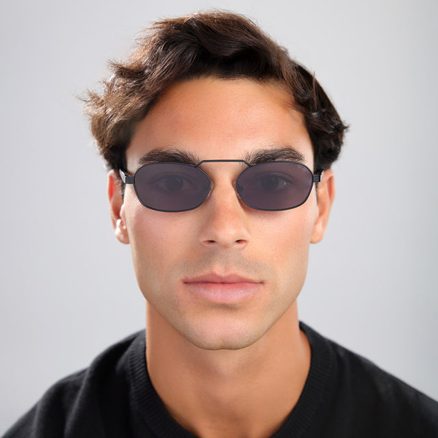Man with brown hair in a black tee wearing Bimini Sunglasses Matte Black with Grey Flat