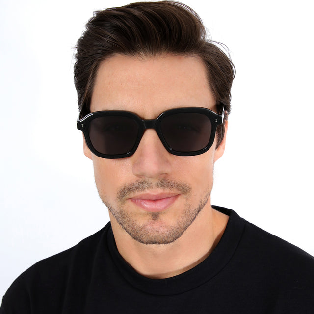 Model with short brown hair combed sideways wearing Bogota Sunglasses Black with Grey Flat