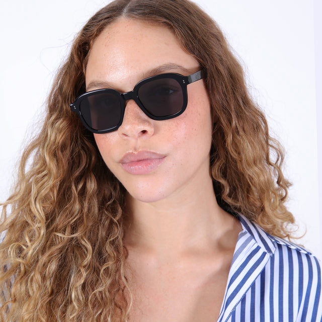 Brunette model with ombré, wavy hair in a striped blouse wearing Bogota Sunglasses Black with Grey Flat