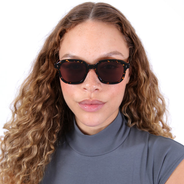 Brunette model with ombré, wavy hair wearing Bogota Sunglasses Flame with Brown Flat