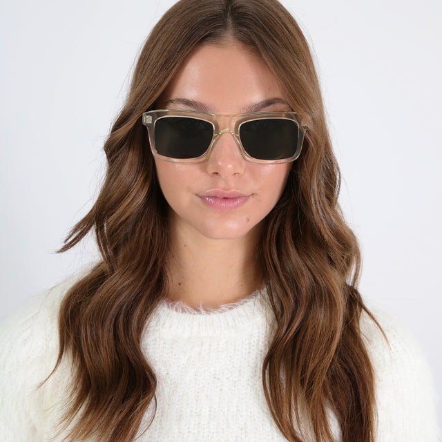 Brunette model in a white sweater wearing Catania Sunglasses Champagne with Olive Flat