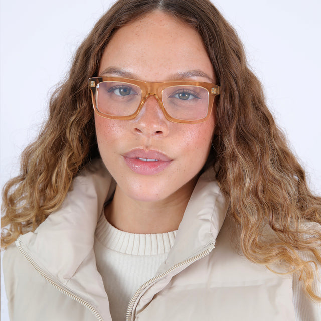 Brunette model with wavy ombre hair in a white puffer jacket wearing Catania Optical Citrine Optical