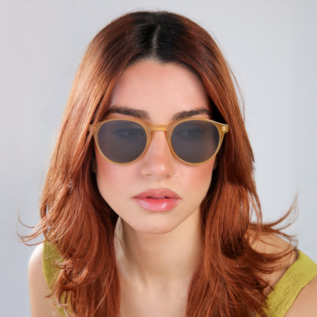 Close up of woman with red hair in a chartreuse blouse looking right Como Sunglasses side view in Blond / Olive