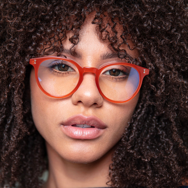 Brunette model with small tight curls wearing Dakota Optical Tangerine Optical