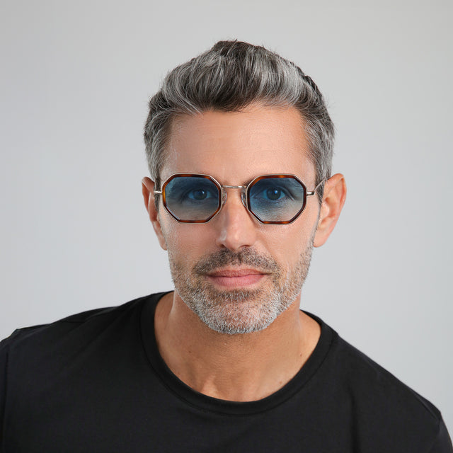 Man with salt and pepper hair and beard in a black shirt wearing Dylan Tate Sunglasses Havana/Gold with Blue Flat Gradient See Through