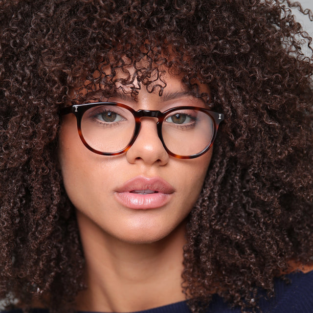 Brunette model with afro-curly hair wearing Eldridge 48 Optical Havana Optical