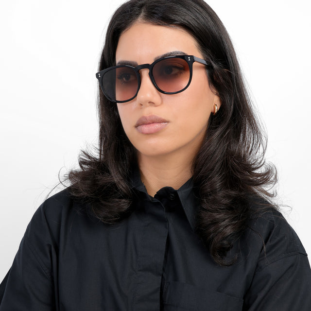 Brunette model with loose curls wearing Eldridge 56 Sunglasses Black with Brown Flat Gradient