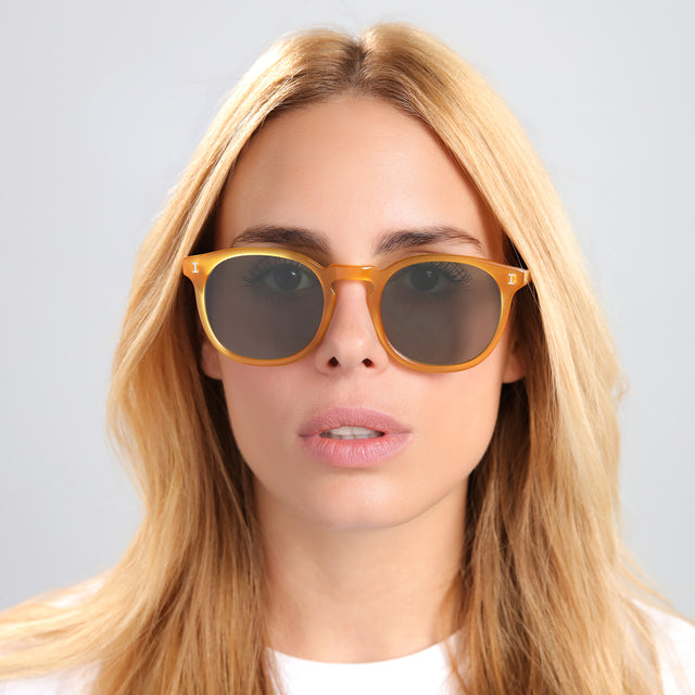 Another angle of blond woman in a white tee wearing Eldridge 56 Sunglasses Honey with Olive Flat