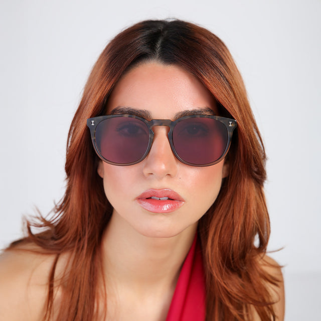 Woman with red hair in a red blouse wearing Eldridge 56 Sunglasses Kale with Plum Flat See Through