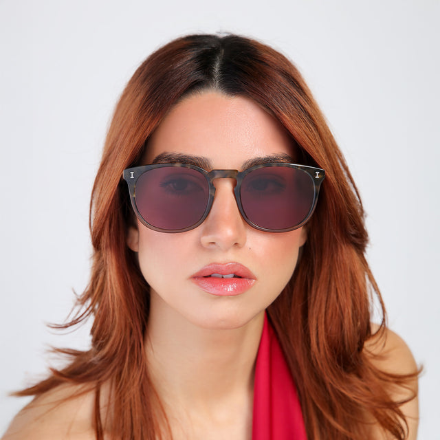 Another angle of woman with red hair in a red blouse wearing Eldridge 56 Sunglasses Kale with Plum Flat See Through
