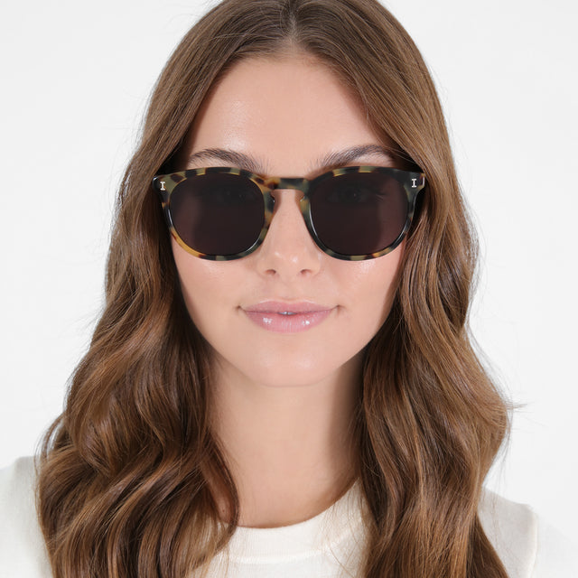 Brunette model with loose curls wearing Eldridge 56 Sunglasses Tortoise with Grey Flat