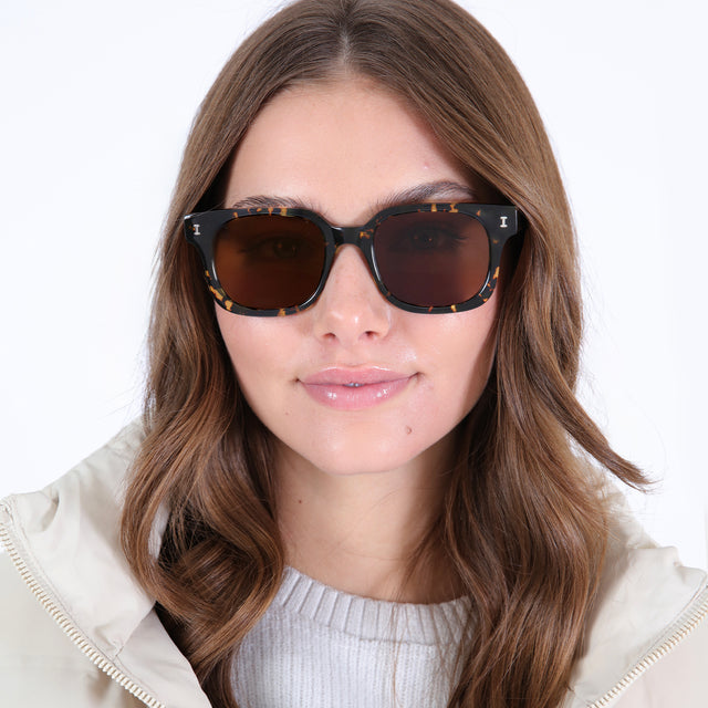 Brunette model with wavy hair wearing Ellison Sunglasses Flame with Brown Flat