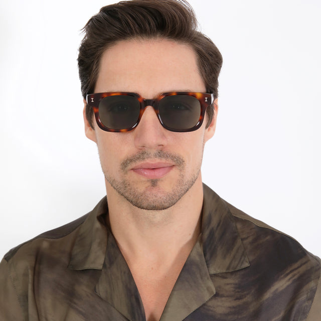 Model with brown hair combed sideways wearing Ellison Sunglasses Havana with Olive Flat