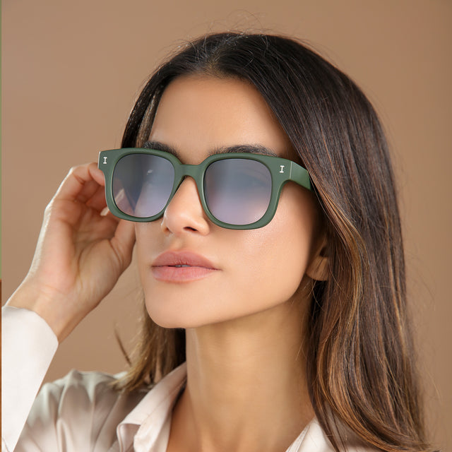 Brunette model in a cream silk blouse glancing left wearing Ellison Sunglasses Matte Eucalyptus with Grey Flat Gradient
