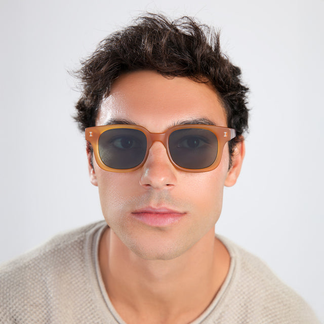 Another angle of man with brown hair in a beige waffled sweatshirt wearing Ellison Sunglasses Matte Honey with Olive Flat