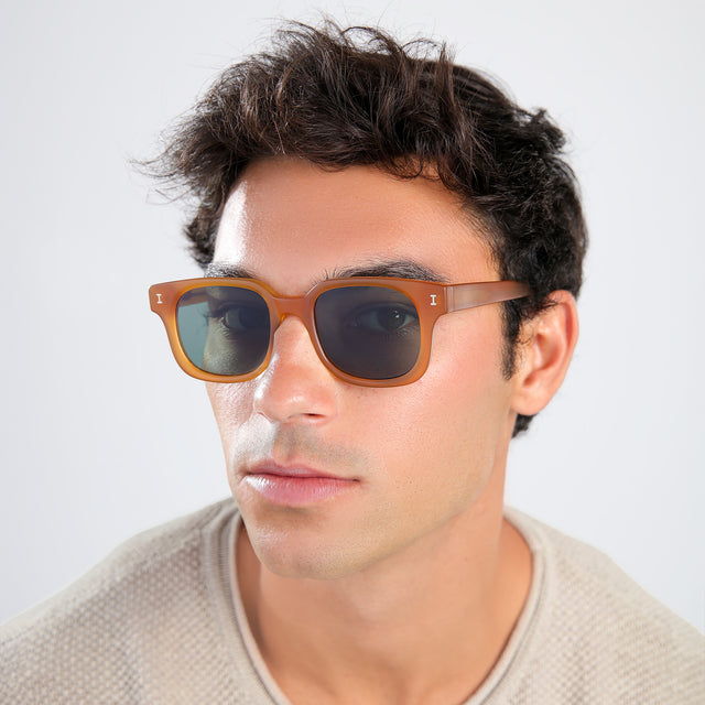 Man with brown hair in a beige waffled sweatshirt wearing Ellison Sunglasses Matte Honey with Olive Flat