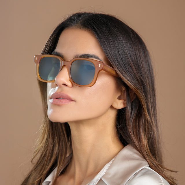 Brunette model in a cream silk blouse glancing left wearing Ellison Sunglasses Matte Honey with Olive Flat