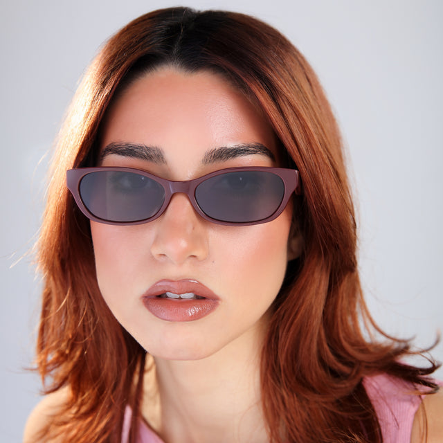Another angle of a woman with red hair in a pink mockneck blouse wearing Encinitas Sunglasses Bordeaux with Grey