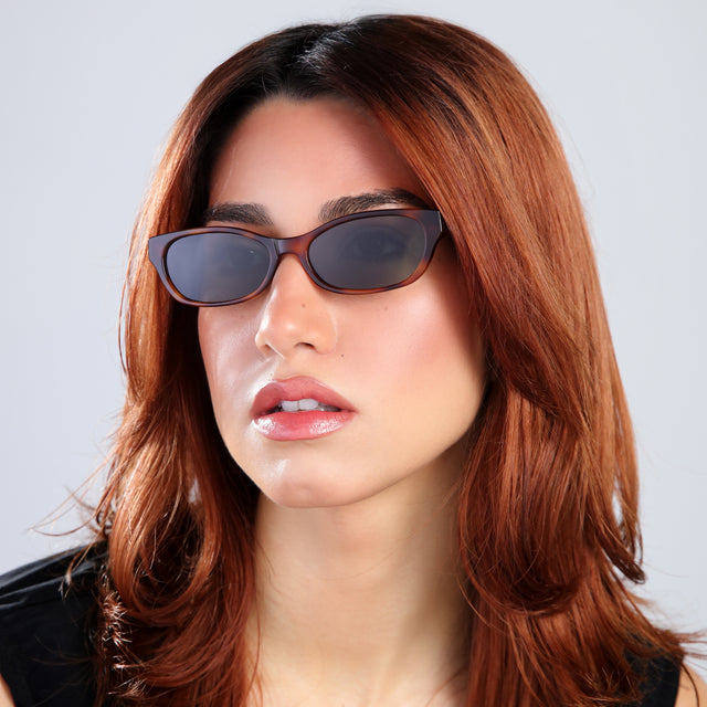 Another angle of a woman with red hair in a black blouse wearing Encinitas Sunglasses Havana with Grey