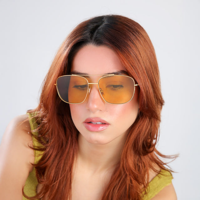 Woman in a chartriusse blouse looking down wearing Frankie Sunglasses Gold with Honey Flat See Through