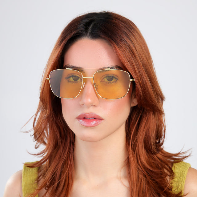Woman with red hair in a chartriusse blouse wearing Frankie Sunglasses Gold with Honey Flat See Through