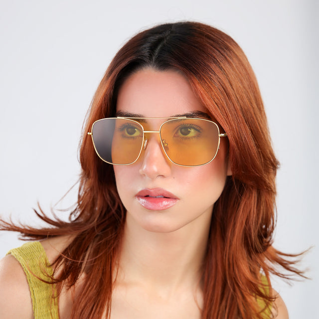 Woman with red hair looking up wearing Frankie Sunglasses Gold with Honey Flat See Through