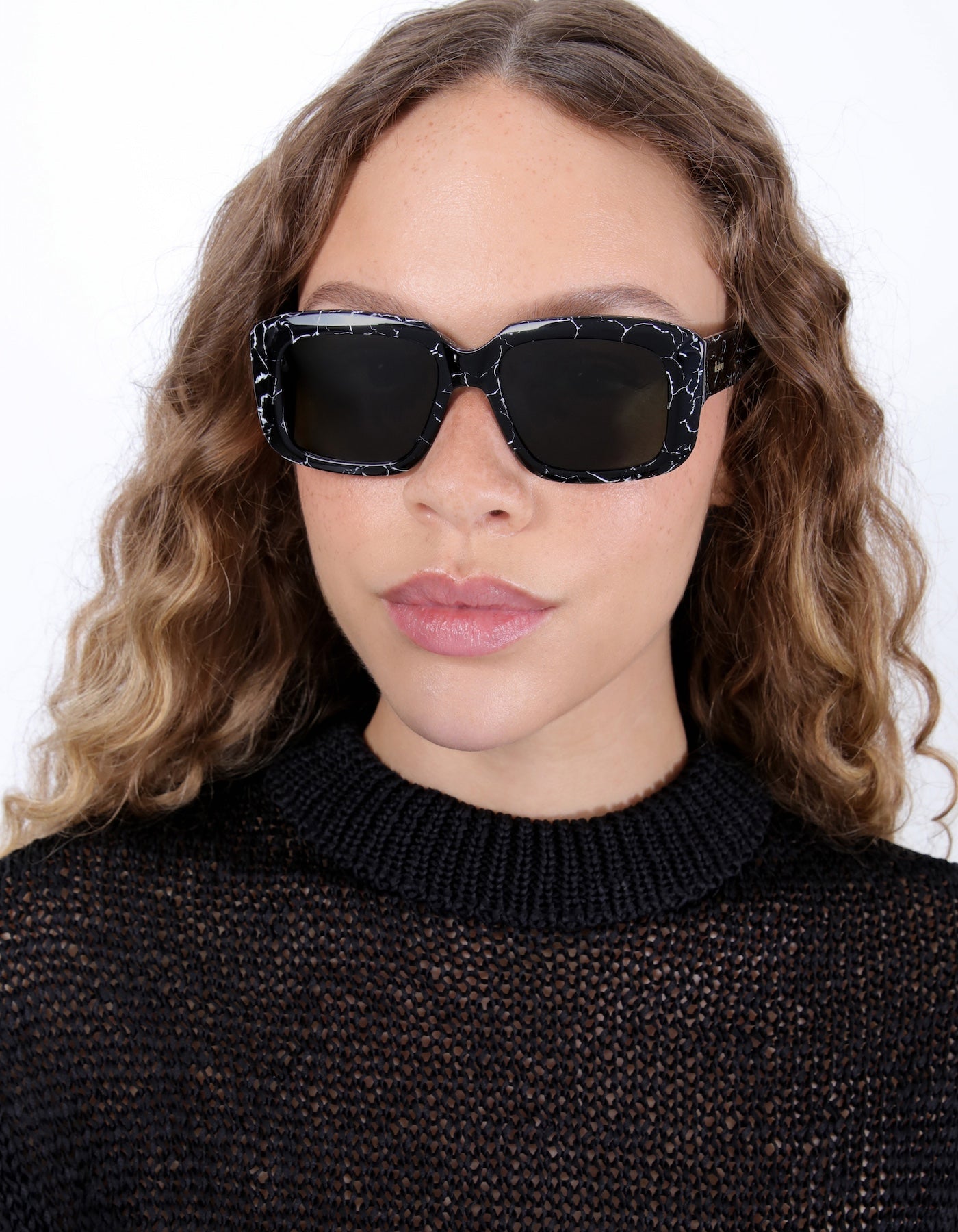Brunette model with ombré, natural curls wearing Geno Sunglasses in Obsidian with Olive