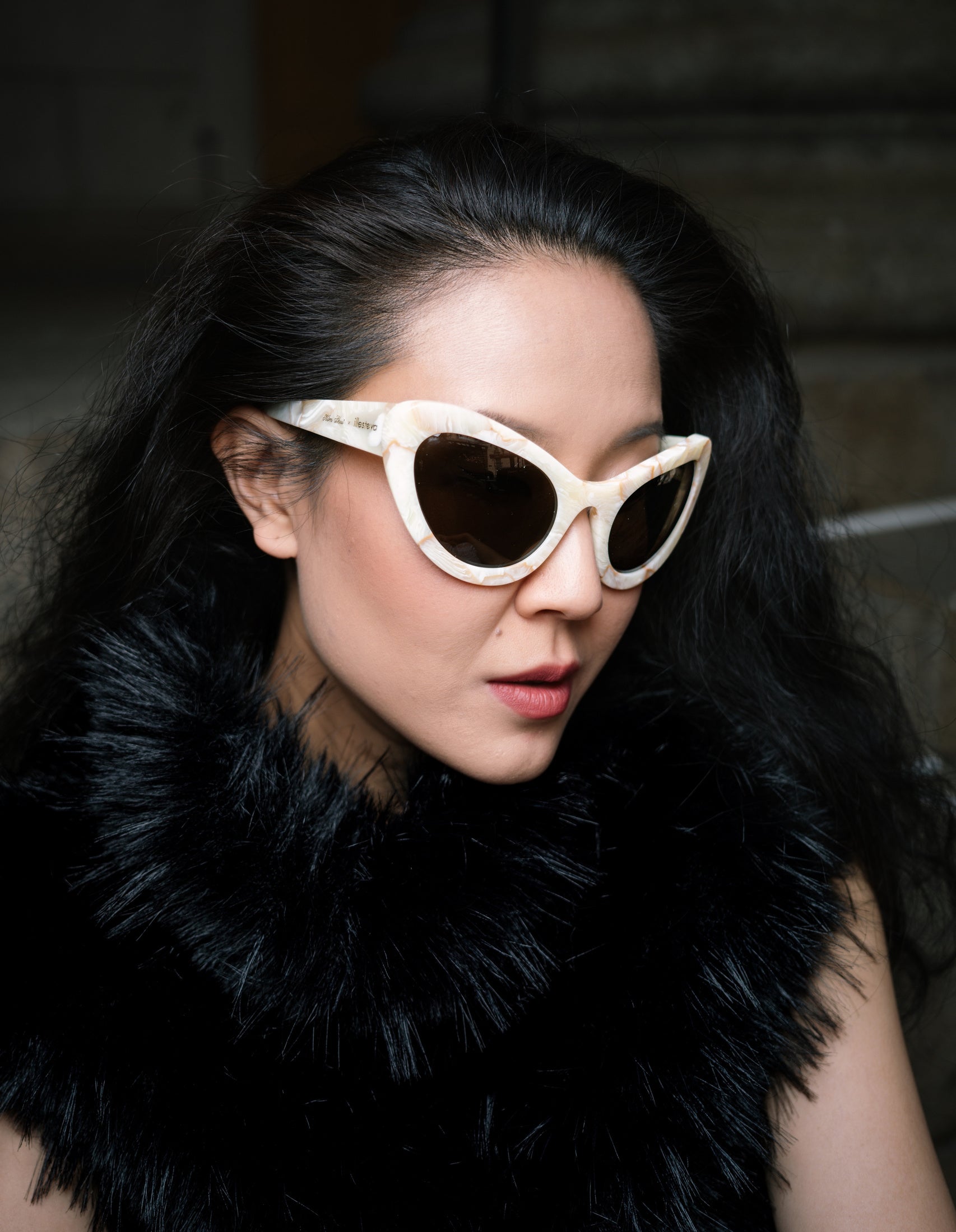 Kim Shui near some steps in a faux fur blouse wearing the Kim Shui x illesteva Sunglasses in Savannah Cream Marble