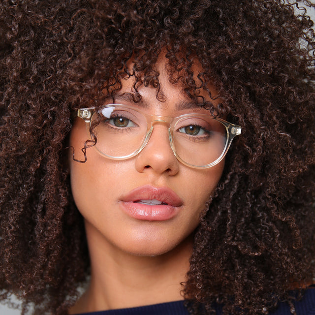 Brunette model with afro-curly hair wearing Lawrence Optical Champagne Optical