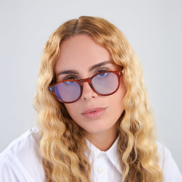 Another angle of model with blonde, wavy hair wearing Lawrence Sunglasses Red Havana with Pale Blue Flat See Through