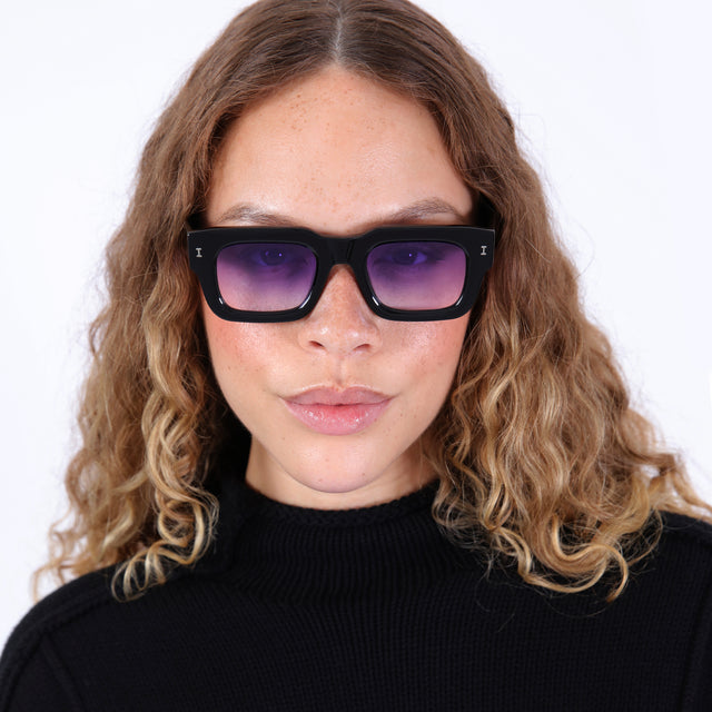 Brunette model with wavy hair in a gray mockneck wearing Lewis 50 Sunglasses Black with Purple Flat Gradient