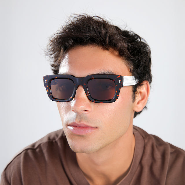 Man with brown hair in a brown shirt wearing Lewis 50 Sunglasses Flame with Brown Flat