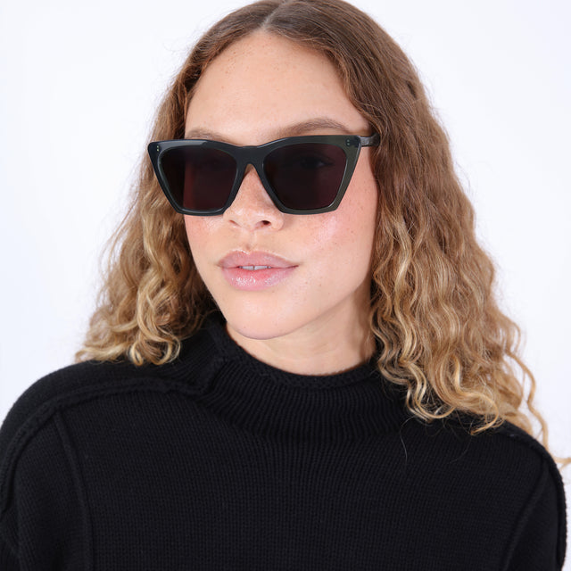 Brunette model with ombre, natural curls wearing Lisbon 57 Sunglasses Pine with Grey