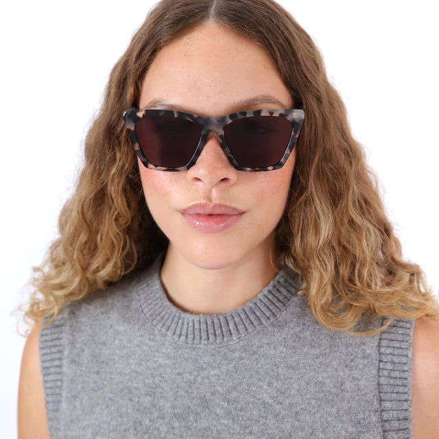 Brunette model with ombre, natural curls wearing Lisbon 57 Sunglasses White Tortoise with Grey
