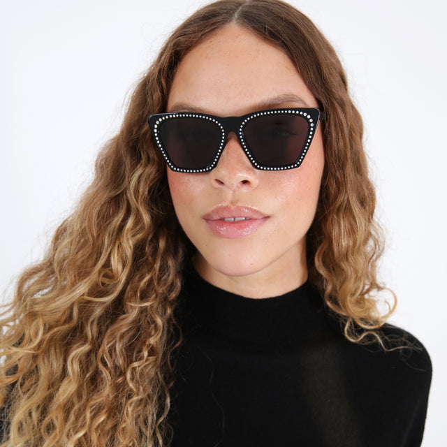 Brunette model with ombré natural curls wearing Lisbon Crystal Sunglasses Black w/ Silver Swarovski Crystals with Grey Flat
