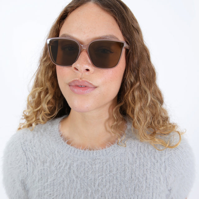 Brunette model with ombre wavy hair wearing Mallorca Sunglasses Thistle with Brown Flat