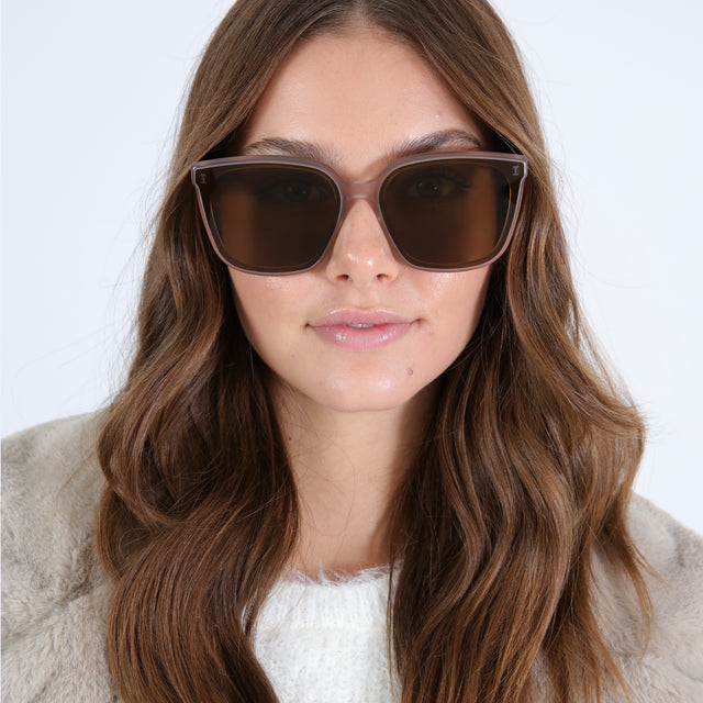 Brunette model with wavy hair wearing Mallorca Sunglasses Thistle with Brown Flat