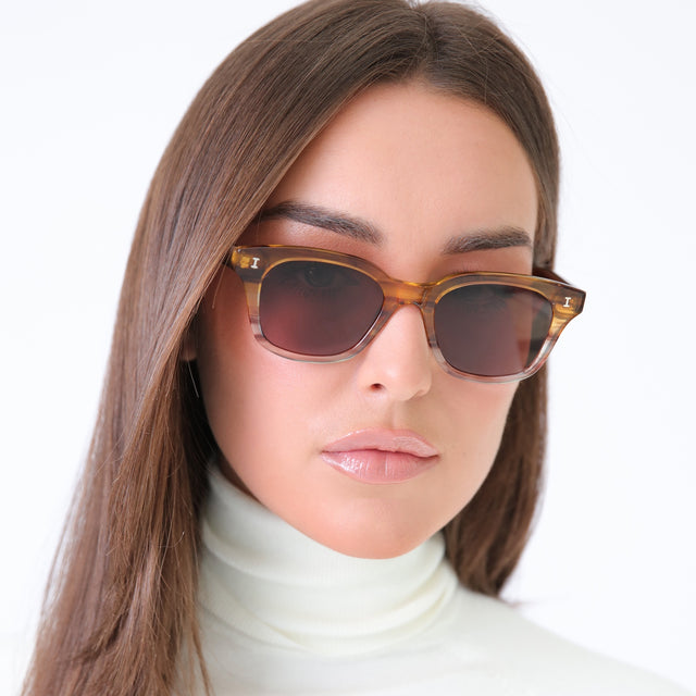 Brunette model in a white turtleneck wearing Melrose Sunglasses Golden Cedar with Brown Flat