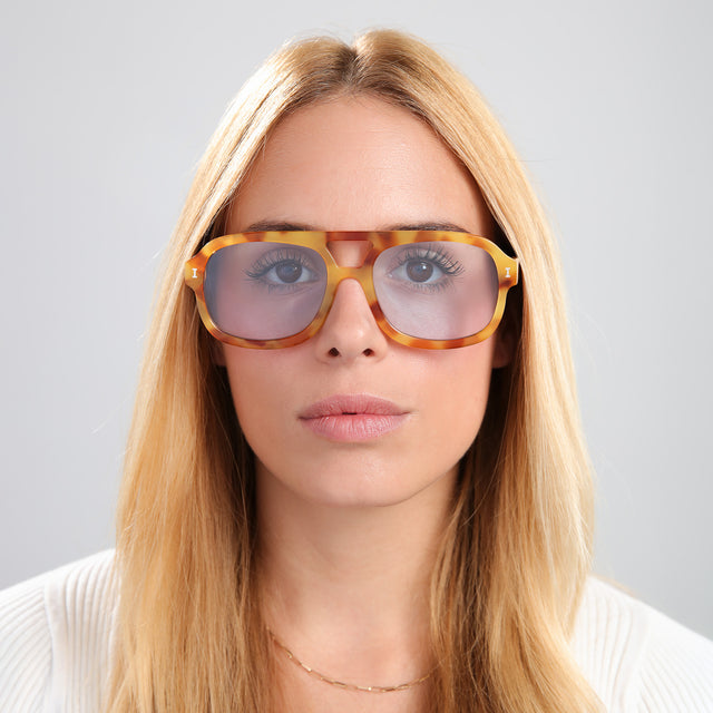 Woman with blonde hair in a white blouse wearing Memphis Sunglasses Amber with Light Blue See Through