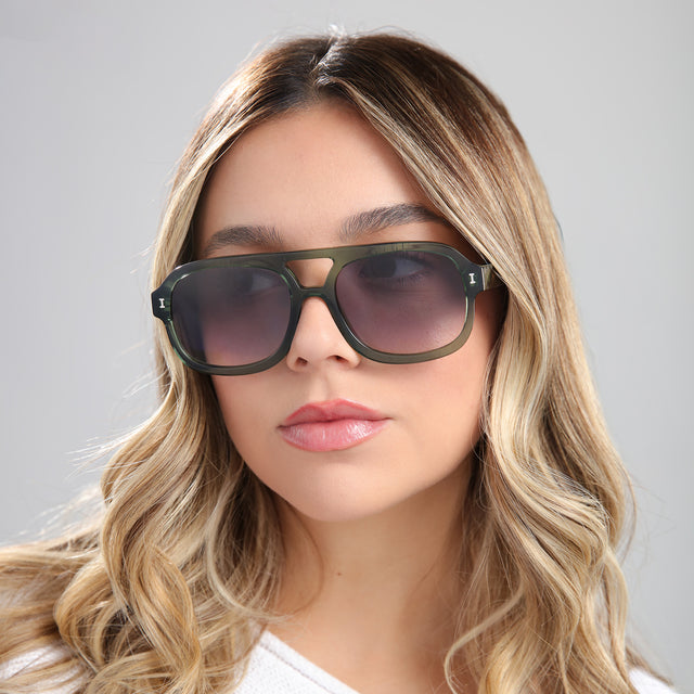 Woman with blonde curled hair wearing Memphis Sunglasses Pine with Grey Gradient