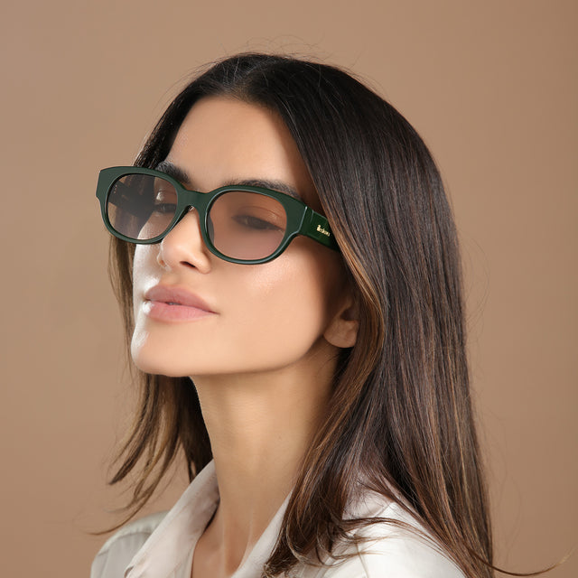 Brunette model in a cream silk blouse looking right wearing Montreal E Sunglasses Evergreen with Taupe Flat Gradient