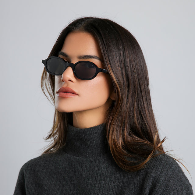 Brunette model in a heather grey cashmere turtleneck glancing left wearing Munich Sunglasses Black with Grey Flat