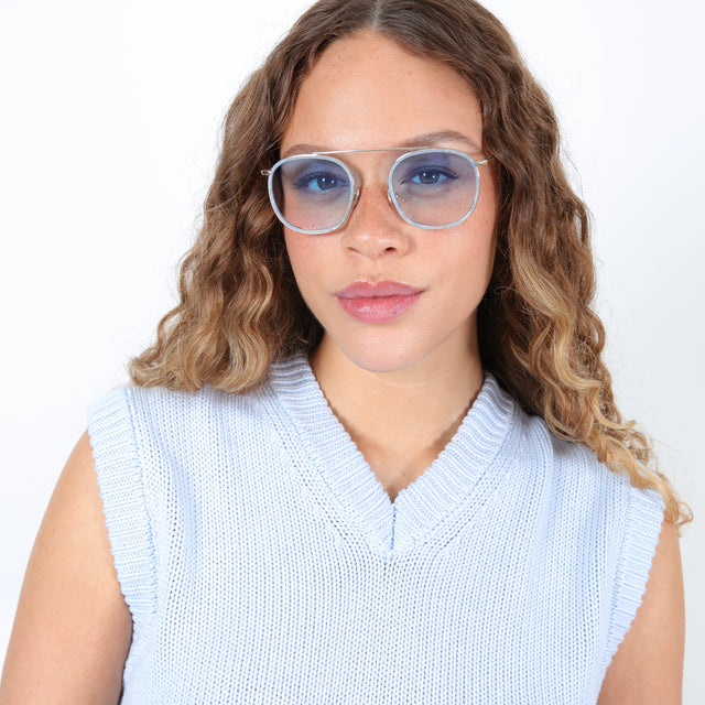 Brunette model with ombré, curled hair wearing Mykonos Ace Sunglasses Celeste/Gold with Blue Flat Gradient See Through