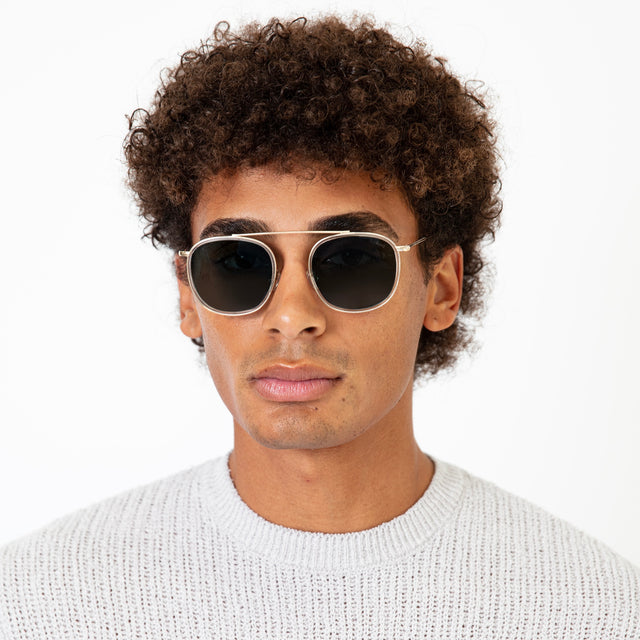 Model with afro-curly hair wearing Mykonos Ace Sunglasses Clear Gold with Olive Flat
