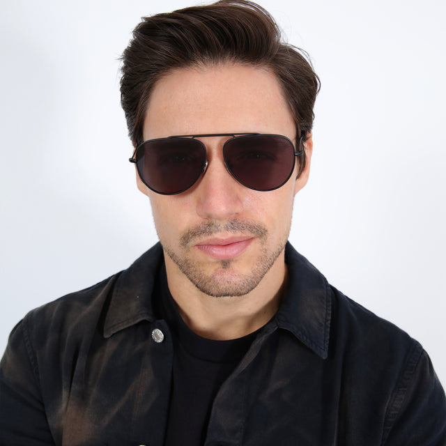 Model with short brown hair wearing Naxos 58 Sunglasses Matte Black with Grey Flat