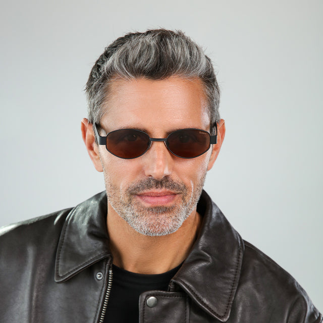 Bearded model wearing Nesso Sunglasses Matte Black with Brown