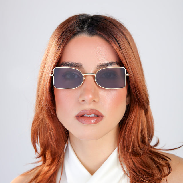 Woman with red hair in a white blouse wearing Nostrand Sunglasses Gold with Grey